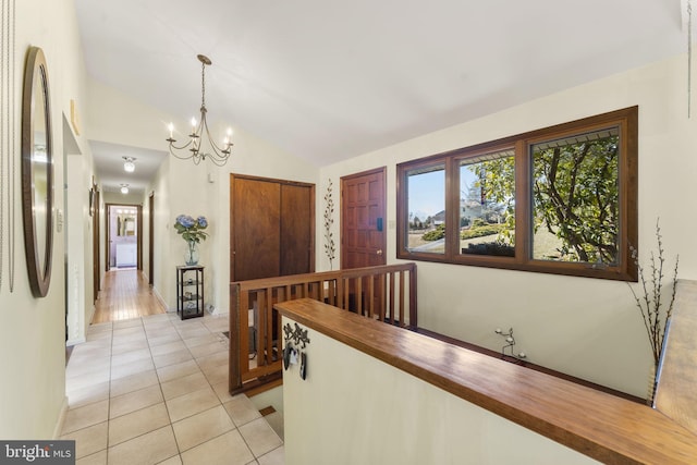 hall featuring light tile patterned floors, lofted ceiling, and an inviting chandelier