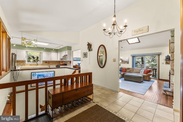 interior space with a wealth of natural light, light tile patterned floors, a chandelier, and baseboards