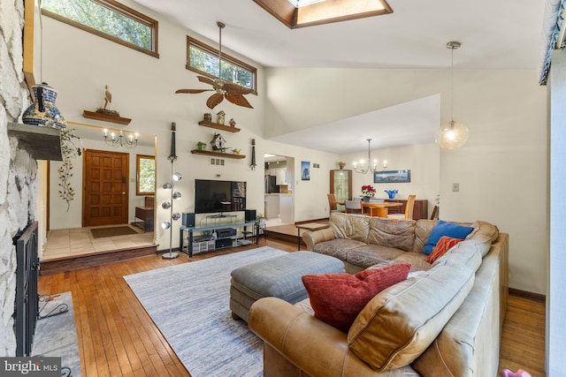 living room featuring plenty of natural light, ceiling fan with notable chandelier, a skylight, and hardwood / wood-style flooring