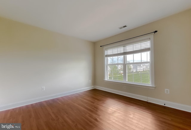 empty room with baseboards, wood finished floors, and visible vents