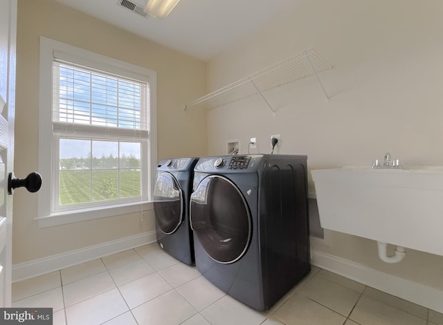 laundry room with laundry area, visible vents, light tile patterned floors, washing machine and dryer, and baseboards