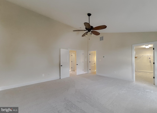 unfurnished bedroom featuring a spacious closet, visible vents, light colored carpet, baseboards, and high vaulted ceiling