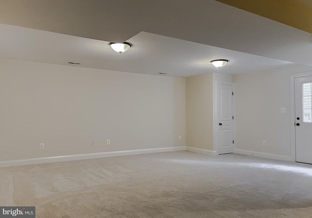 spare room featuring baseboards and light colored carpet
