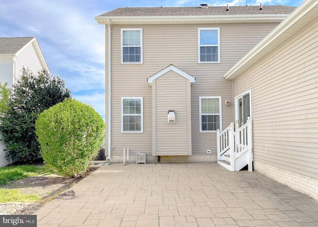 back of house featuring entry steps, a shingled roof, and a patio