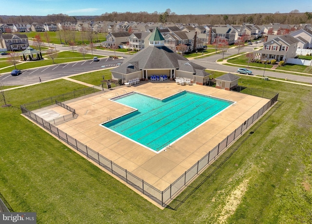 community pool featuring a yard, a residential view, a patio area, and fence