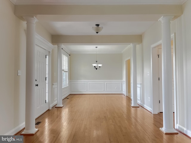 entryway featuring a wainscoted wall, visible vents, a chandelier, light wood-style floors, and ornate columns