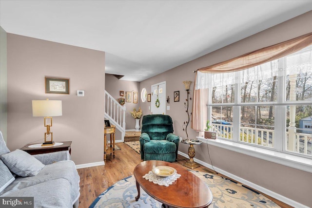 living room with stairs, baseboards, and wood finished floors