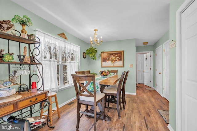 dining space with an inviting chandelier, wood finished floors, baseboards, and visible vents