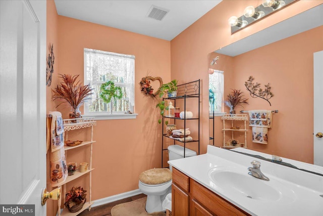 bathroom with vanity, toilet, baseboards, and visible vents