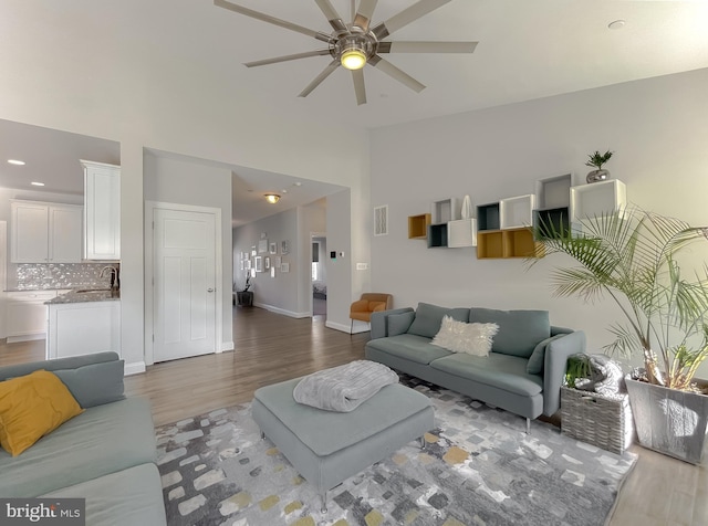 living area featuring visible vents, baseboards, light wood-style floors, high vaulted ceiling, and a ceiling fan