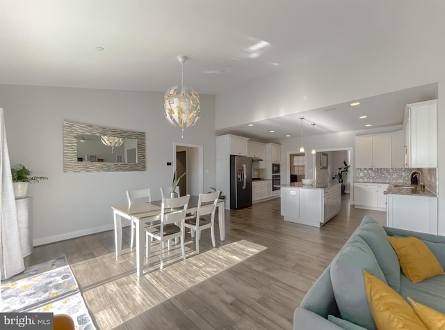 dining space with vaulted ceiling, recessed lighting, light wood-type flooring, and baseboards