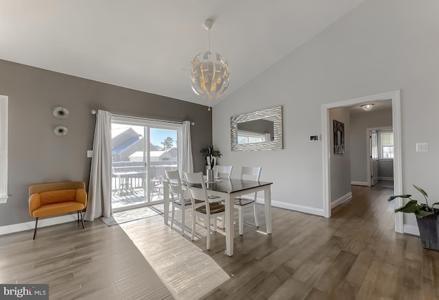 dining area with an inviting chandelier, wood finished floors, baseboards, and high vaulted ceiling