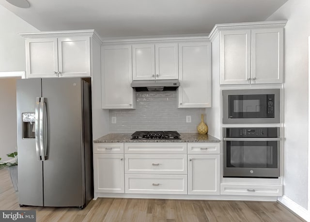 kitchen featuring under cabinet range hood, white cabinetry, stainless steel appliances, and light stone countertops