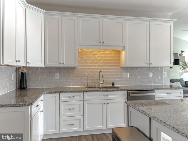 kitchen featuring a sink, stone counters, stainless steel dishwasher, and white cabinetry