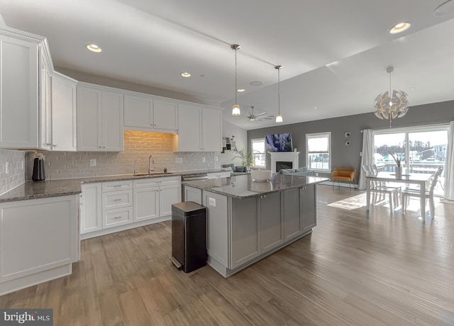 kitchen with a kitchen island, white cabinets, stainless steel dishwasher, and a sink