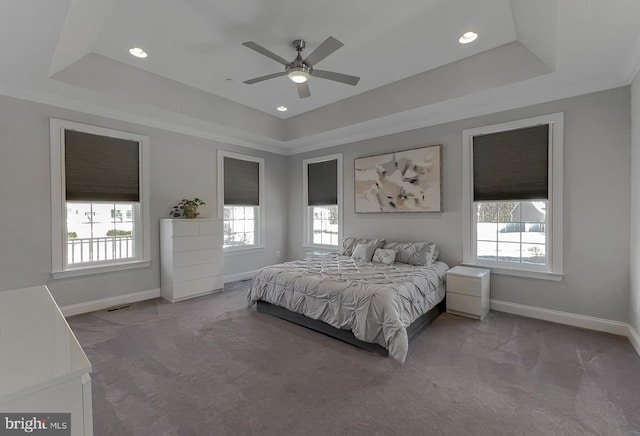 carpeted bedroom featuring a tray ceiling and baseboards