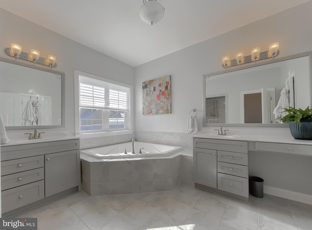 bathroom featuring two vanities, a bath, and a sink