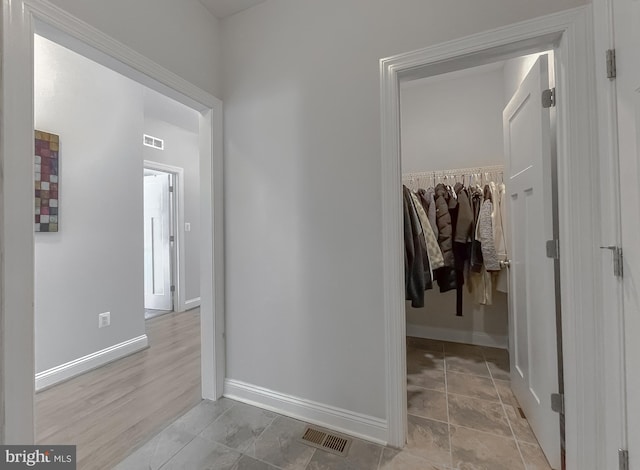 hallway with baseboards and visible vents