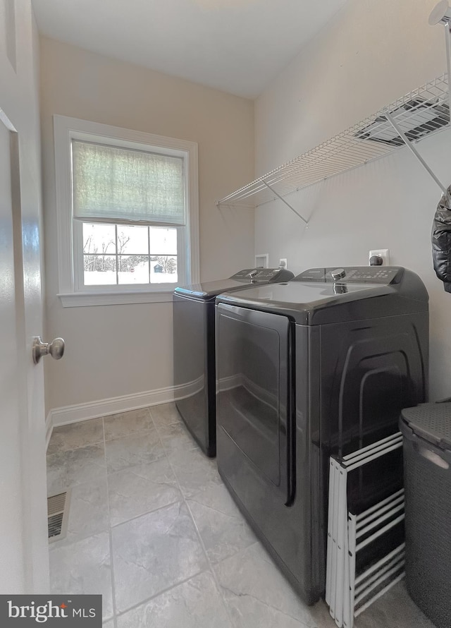 clothes washing area with laundry area, washer and dryer, and baseboards