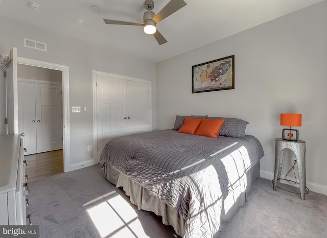 carpeted bedroom featuring a closet, visible vents, a ceiling fan, and baseboards