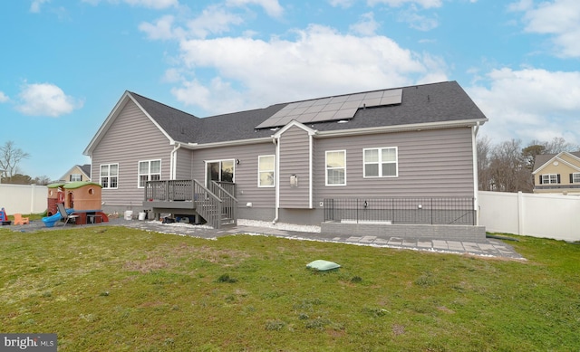 back of property featuring a yard, roof mounted solar panels, a fenced backyard, and a patio area