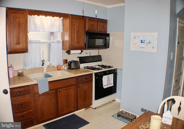 kitchen with visible vents, black microwave, light floors, range with gas stovetop, and a sink