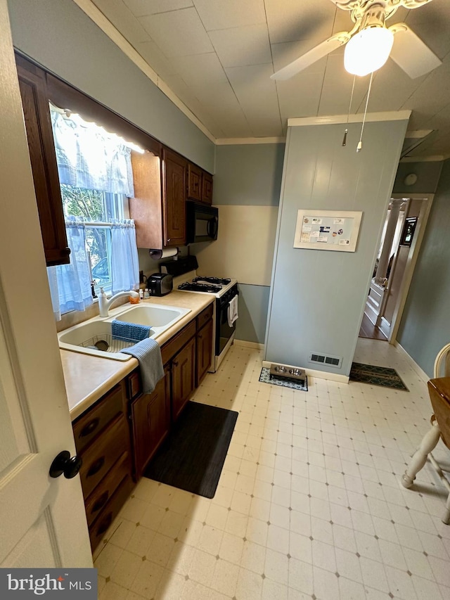 kitchen featuring visible vents, crown molding, range with gas cooktop, black microwave, and light floors