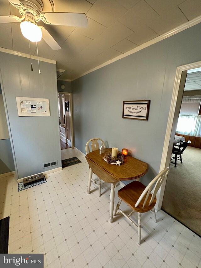 dining area with tile patterned floors, visible vents, crown molding, and a ceiling fan