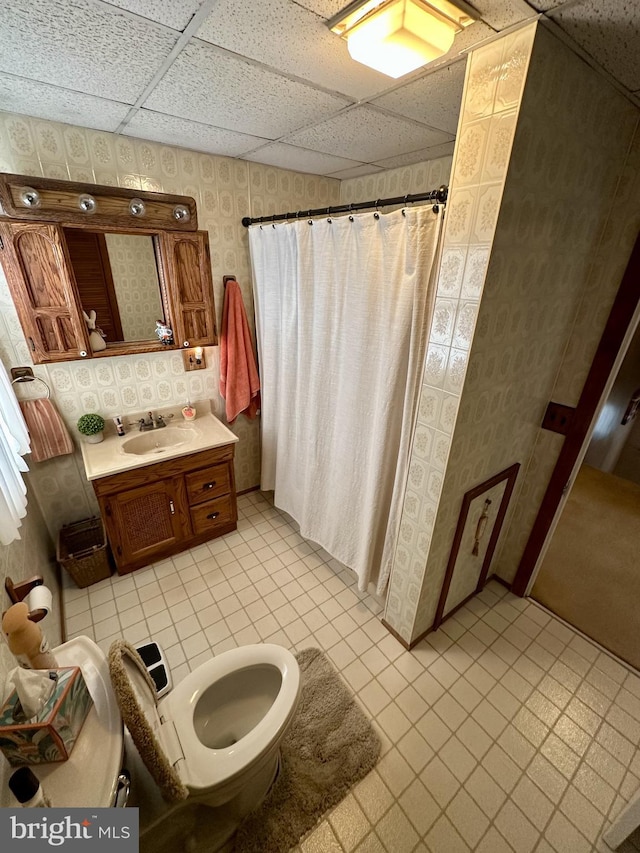 full bathroom with a drop ceiling, curtained shower, and wallpapered walls