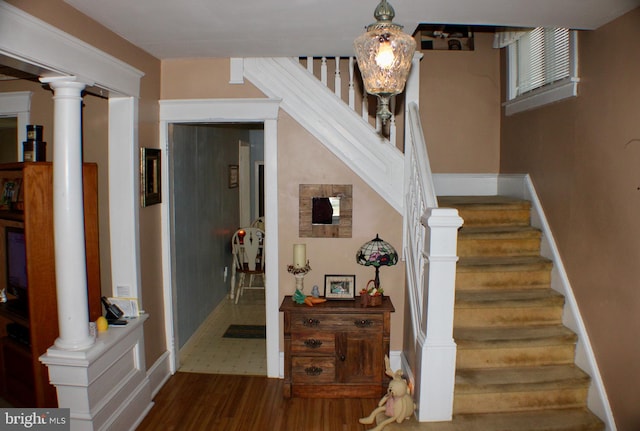 stairway featuring decorative columns, baseboards, and wood finished floors