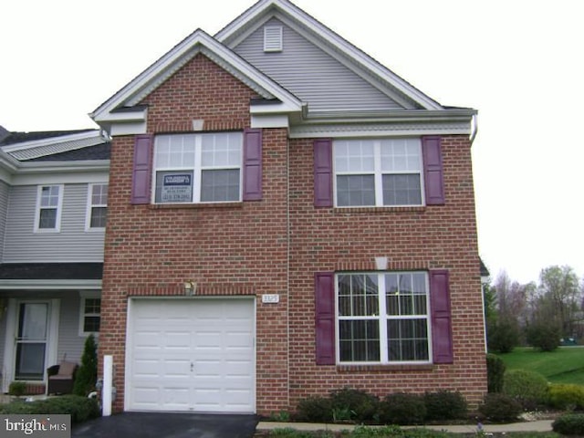 traditional-style house featuring aphalt driveway, brick siding, and an attached garage