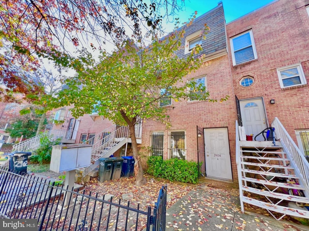 view of property with brick siding, stairs, and fence