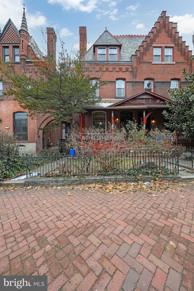 view of front of house featuring a fenced front yard, a high end roof, and brick siding