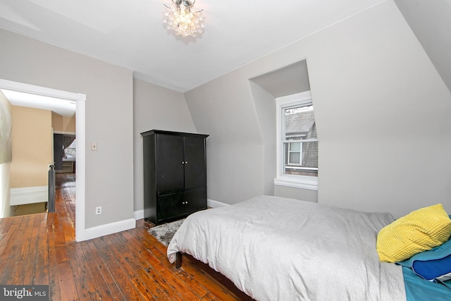 bedroom with baseboards, an inviting chandelier, and hardwood / wood-style floors