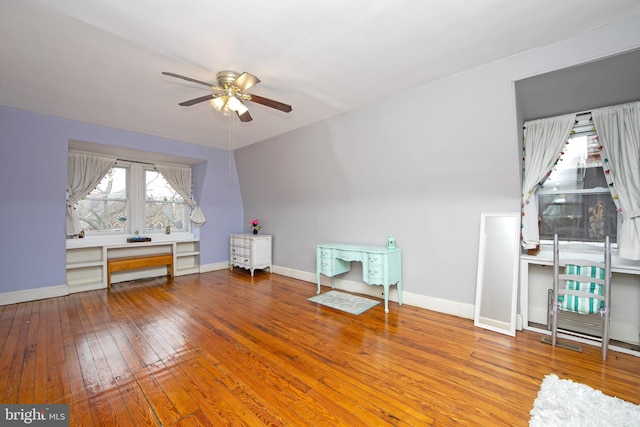 interior space with a ceiling fan, baseboards, and wood-type flooring