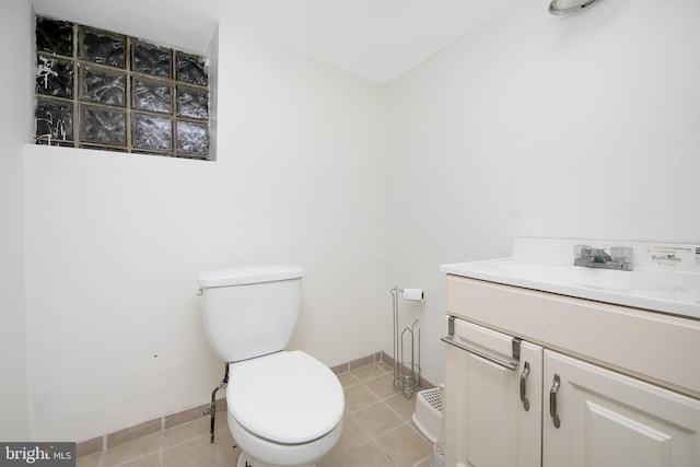 half bath with tile patterned floors, toilet, vanity, and baseboards