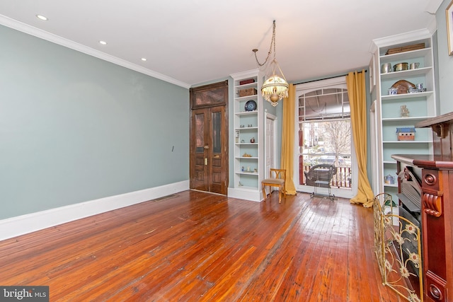 spare room featuring visible vents, crown molding, baseboards, an inviting chandelier, and hardwood / wood-style flooring