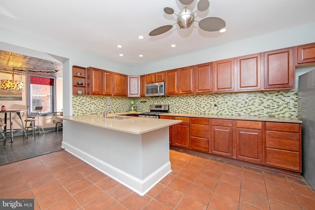 kitchen with a sink, backsplash, light countertops, appliances with stainless steel finishes, and open shelves