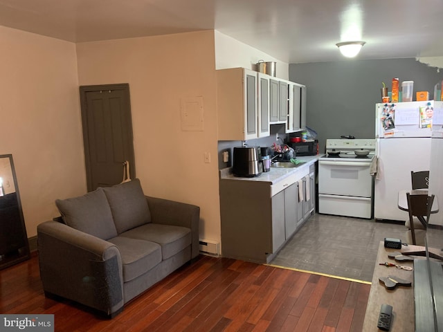 kitchen featuring a baseboard radiator, light countertops, wood finished floors, white appliances, and a sink