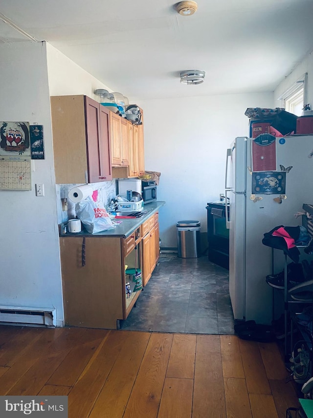 kitchen with dark wood-style floors, brown cabinets, freestanding refrigerator, and a baseboard radiator