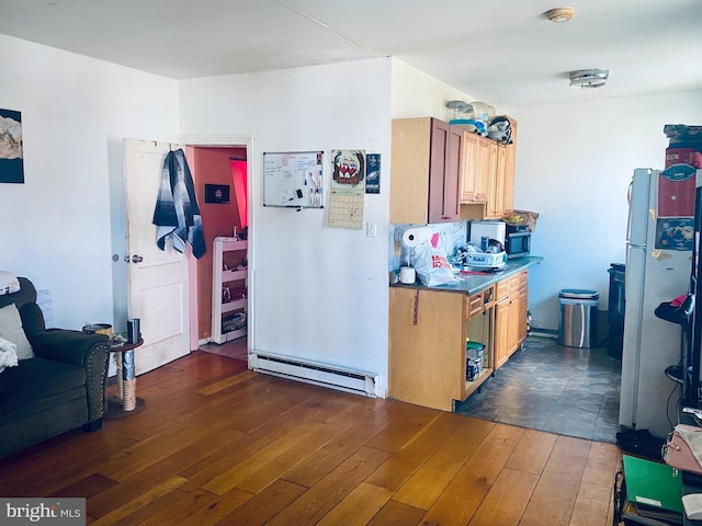 kitchen with dark wood finished floors, baseboard heating, and freestanding refrigerator