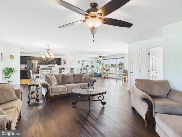 living area with wood finished floors and ceiling fan with notable chandelier