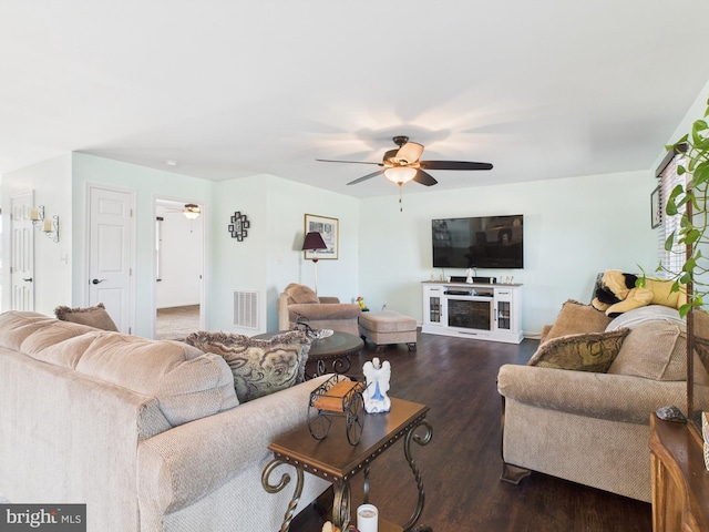 living room featuring visible vents, dark wood-type flooring, and a ceiling fan