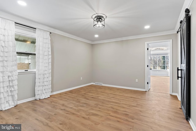 empty room with baseboards, light wood-style flooring, recessed lighting, ornamental molding, and a barn door