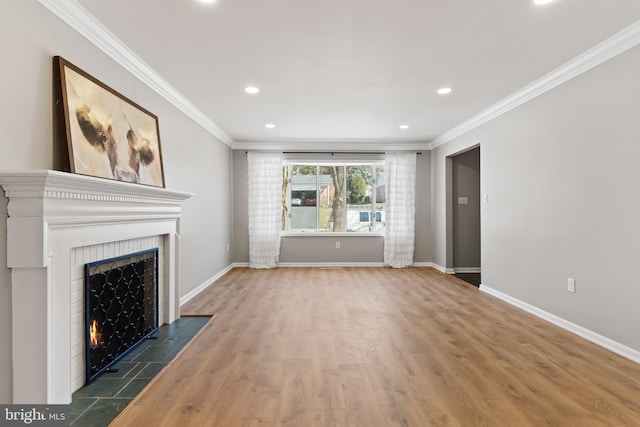 unfurnished living room featuring a tile fireplace, wood finished floors, baseboards, and ornamental molding