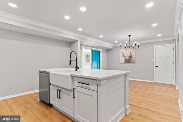 kitchen featuring light wood-style floors, stainless steel dishwasher, a center island with sink, and crown molding