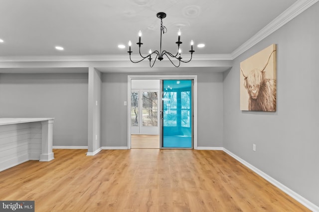 unfurnished dining area featuring baseboards, a notable chandelier, wood finished floors, and crown molding