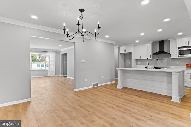 kitchen with stainless steel microwave, visible vents, wall chimney range hood, light countertops, and ornamental molding