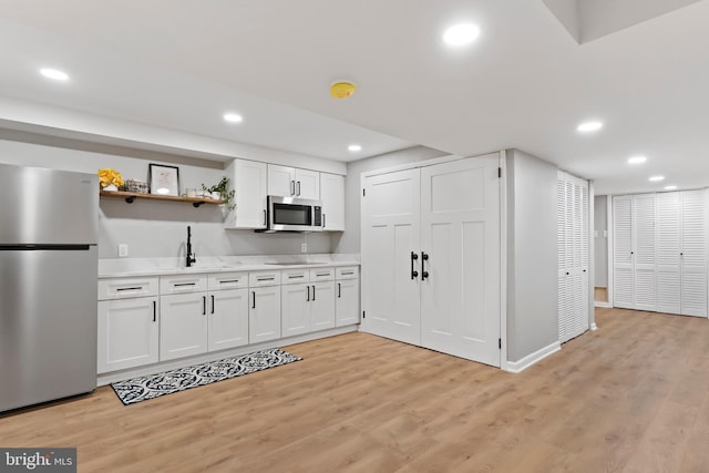 kitchen with light wood finished floors, open shelves, recessed lighting, stainless steel appliances, and light countertops