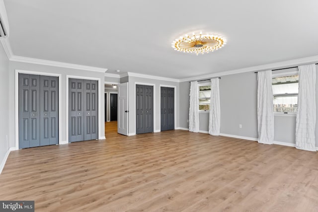 unfurnished bedroom featuring light wood-style flooring, two closets, and baseboards